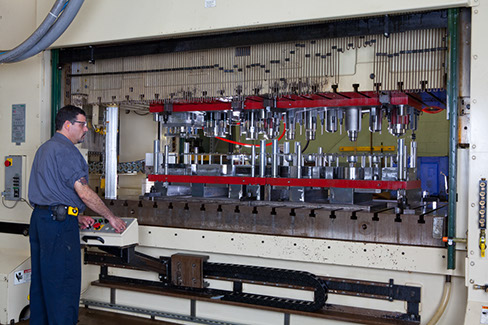 A larson tool & stamping employee operating a progressive die machine.