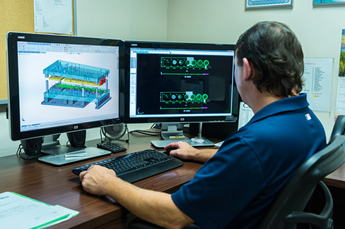 A Larson Tool & Stamping employee reviewing a custom tool design in CAD.
